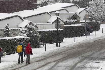 Una pareja camina por una calle nevada en el pueblo madrileño de Navacerrada.