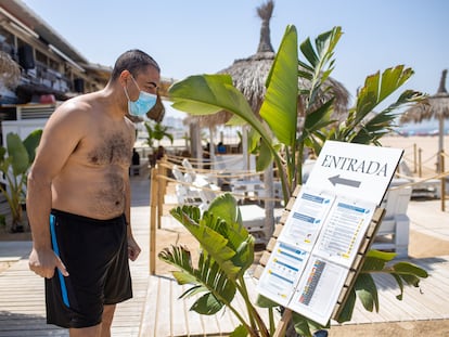 Un turista lee las instrucciones de la covid-19 antes de entrar en el chiringuito Palapa Beach en Valdelagrana  Puerto de Santa María (Cádiz). En vídeo, la situación de los chiringuitos en la Costa del Sol. JUAN CARLOS TORO