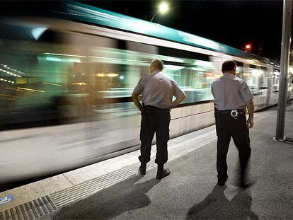 Dos vigilantes de seguridad inspeccionan, la madrugada del viernes al sábado, la estación del tranvía de Sant Adrià de Besòs.