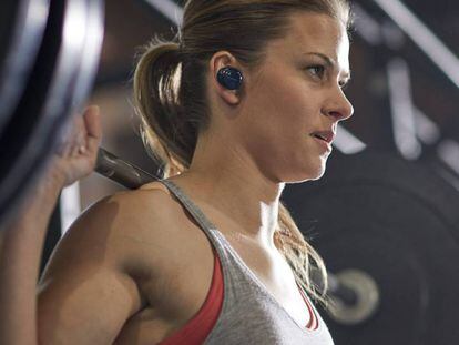 Una mujer levanta pesas en el gimnasio mientras escucha música a través de los auriculares Bose SoundSport Free.