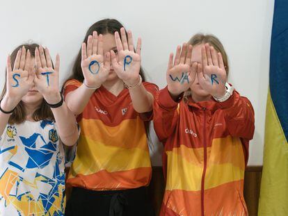 Tres niñas ucranianas muestran sus manos con el mensaje Stop War (paren la guerra), este martes en la localidad de El Tiemblo (Ávila).