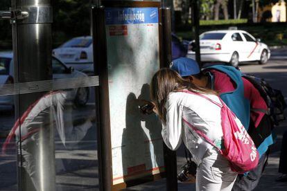 Una pareja de turistas miran un plano del metro de Madrid.