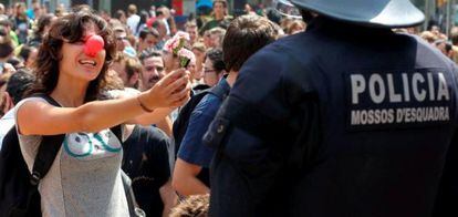 Una joven sostiene un clavel en su mano ante la presencia de un agente de los Mossos d'Esquadra