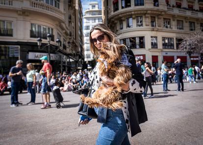 Una joven lleva a su perro en brazos durante las fallas. 