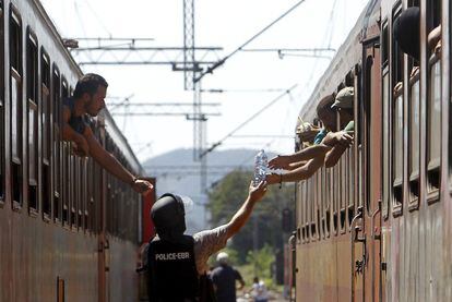 Un oficial de policia passa una ampolla als immigrants que emprenen el viatge amb tren cap a Sèrbia, a l'estació macedònia de Gevgelija. Només al juliol 107.500 persones (principalment de Síria, l'Afganistan, Eritrea, l'Iraq i el Sudan del Sud) han travessat el Mediterrani per arribar a territori europeu, segons Frontex.