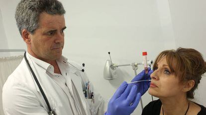 El m&eacute;dico Ruiz Maroto toma una muestra a una mujer para diagnosticar la gripe.