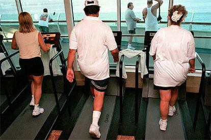 Pasajeros de un crucero siguen un programa de ejercicio físico en el gimnasio.