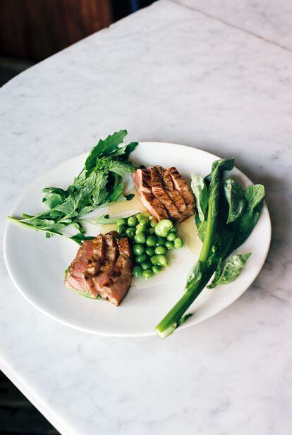 Grilled Berkshire pork with braised English peas, fava beans in pork broth and fresh leaves.  Dish by chef Ignacio Mattos, from his restaurant Estela, in an image provided by the establishment.