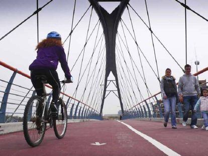 Ciclista y peatones utilizan una de las pasarelas del anillo verde ciclista de Madrid.