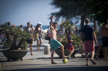 Turistes jugant amb una pilota al passeig marítim de Barcelona.