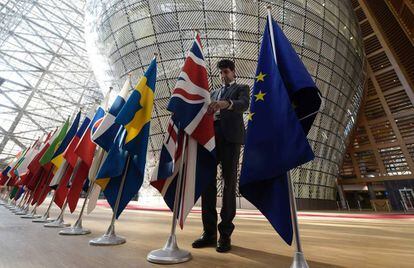Un trabajador coloca las banderas antes de la cumbre de l&iacute;deres en Bruselas.