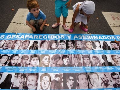 Un grupo de niños mira fotografías de víctimas de la dictadura argentina.