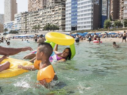 Mario (a la izquierda) juega con Alexander (centro) y Andrea (subida en el flotador), en el agua de la playa de Benidorm.
