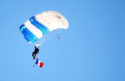 Un paracaídista de las fuerzas armadas norteamericanas lleva una bandera de Francia