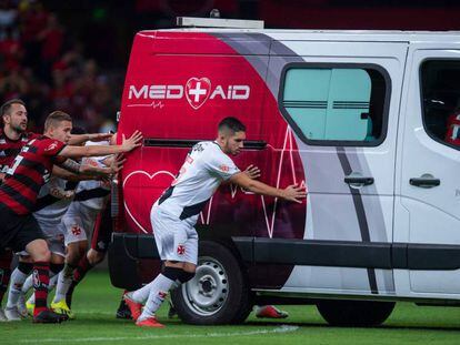 Un grupo de jugadores empuja una ambulancia para ayudarla a salir del campo.