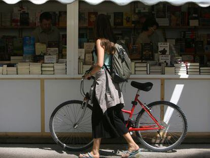 Una jove amb la se seua bicicleta passeja per la Fira del Llibre de Val&egrave;ncia.