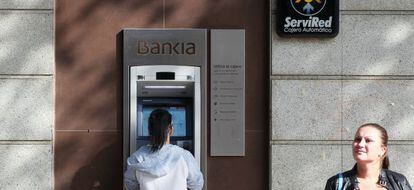 Una persona sacando dinero de un cajero de Bankia