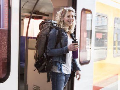 Una joven mochilera se baja de un tren.