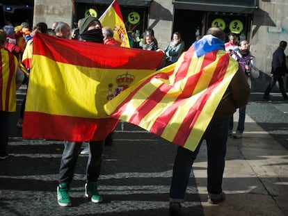 Un ciudadano con una bandera estelada colgada del cuello cruza la plaza Sant Jaume junto a otras personas que portan banderas españolas, en Barcelona.
