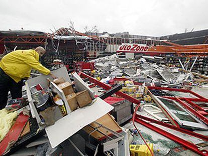 Un empleado de un gran almacén de repuestos de coche limpia el recinto, medio derruido tras el paso del huracán <i>Charley.</i>