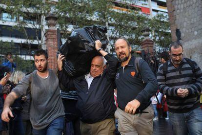 Varios hombres transportan urnas a un centro de votación de Barcelona.