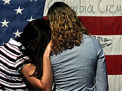 Dos adolescentes leen los mensajes escritos en una bandera por los asistentes a la ceremonia de homenaje a la tripulación del <i>Columbia</i> celebrada el martes en Houston.