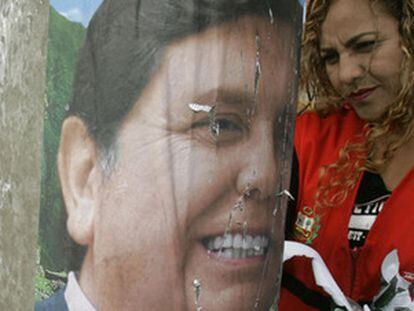 Una mujer retira un cartel electoral del candidato presidencial Alan García el día anterior a las elecciones en junio de 2006 en Perú