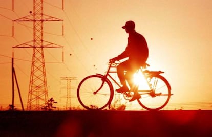 Un ciclista pasa delante de las torretas eléctricas en el atardecer de Nairobi.