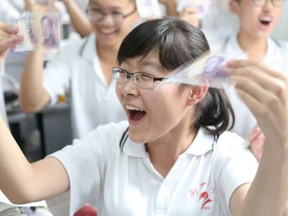 Una estudiante de selectividad china muestra un billete de cinco yuanes antes de su examen. En China se considera que da suerte. REUTERS