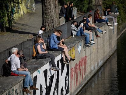 Gente pasea, charla y mira el móvil en Berlín, durante la pandemia del coronavirus.