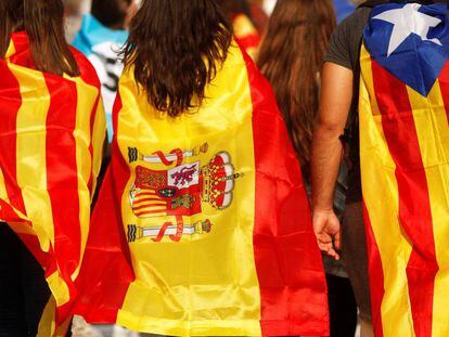 Tres jóvenes acuden a una manifestación en Barcelona con una senyera, una bandera de España y una estelada.