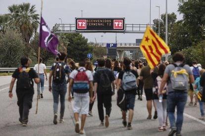 Viajeros y manifestantes caminan hacia el aeropuerto de El Prat, este lunes