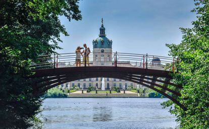 Una pareja hace una foto del palacio de Charlottenburg desde un puente sobre el río Spree, en Berlín.