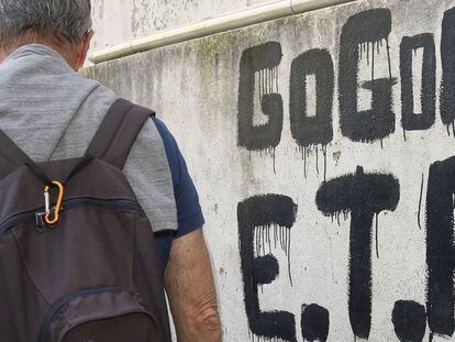 Un home camina al costat d'una pintada que resa "ETA, País Basc i Llibertat".