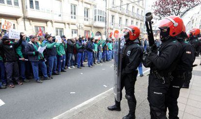 Agentes de la Ertzaintza vigilan la sede de la Cámara frente a los trabajadores concentrados.