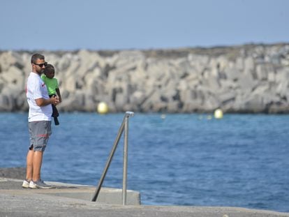 Un voluntario de Cruz Roja pasea con un menor en el puerto de la Restinga, en la isla de El Hierro, el pasado lunes.