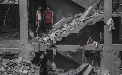 Varios hombres esperan en las escaleras de un edificio derruido por los bombardeos en la ciudad de Gaza, este viernes.