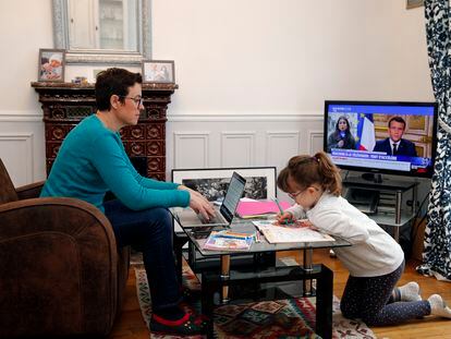 Una mujer teletrabaja desde el salón de su casa en París mientras su hija juega a su lado.