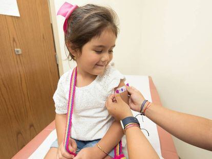 Una enfermera coloca una tirita en el brazo de una pequeña que acaba de recibir una vacuna.