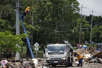 Dos operarios reparan líneas telefónicas dañadas por las inundaciones en Brisbane.