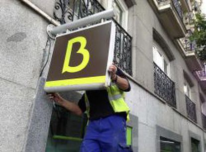 Un trabajador cuelga el logotipo de Bankia en una sucursal.