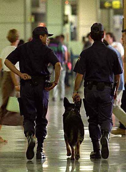Dos policías patrullan con un perro en el vestíbulo del aeropuerto de Barajas.