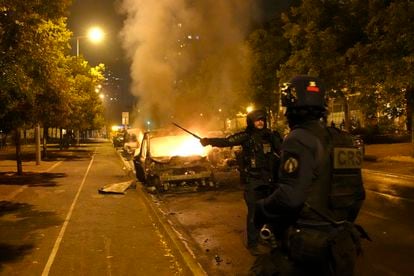 Agentes antidisturbios pasan junto a vehículos en llamas durante los enfrentamientos en Nanterre, a las afueras de París, la noche del miércoles.