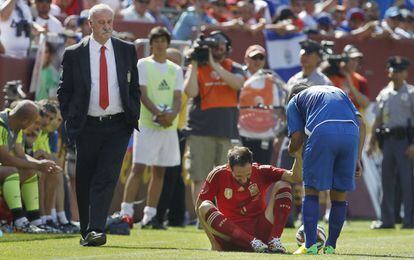 Juanfran es ayudado por un jugador del equipo rival. Al fondo, Del Bosque, el seleccionador de España.