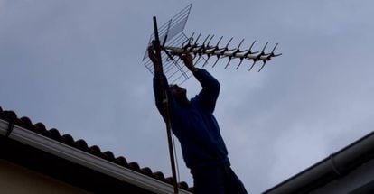 Un hombre ajusta la antena de televisión sobre el tejado en una localidad madrileña. 