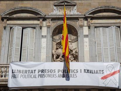 Balcón del edificio de la Generalitat con pancarta con lazo blanco y franja roja. 