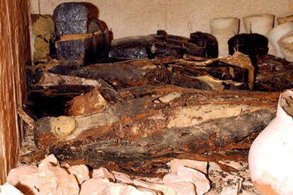 Un sarcófago con forma humana en el suelo junto a otros tres sarcófagos y diversos objetos funerarios en la tumbra recién descubierta en el Valle de los Reyes.