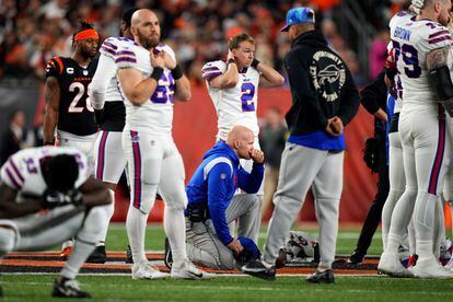 El entrenador de los Buffalo Bills, Sean McDermott, se arrodilla mientras  Damar Hamlin recibe asistencia médica tras desplomarse en el campo.