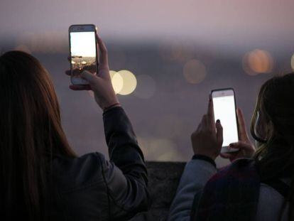 Dos j&oacute;venes toman im&aacute;genes con sus m&oacute;viles en Barcelona. 