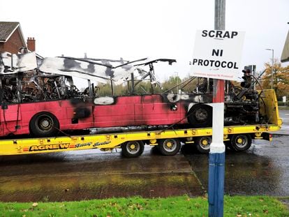 Los restos del autobús incendiado en Belfast, este lunes. Frente al vehículo, un cartel exige la retirada del Protocolo de Irlanda del Norte.